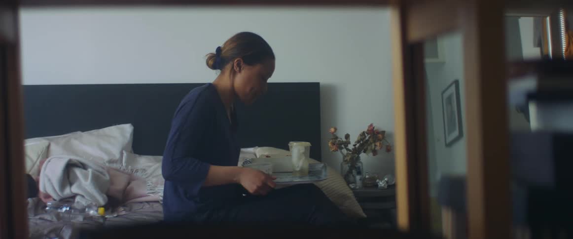 A woman is sitting on a bed in her room
