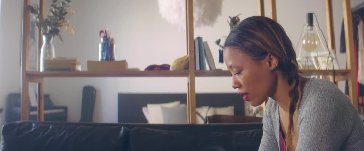 A woman sits on a couch in her home looking at something