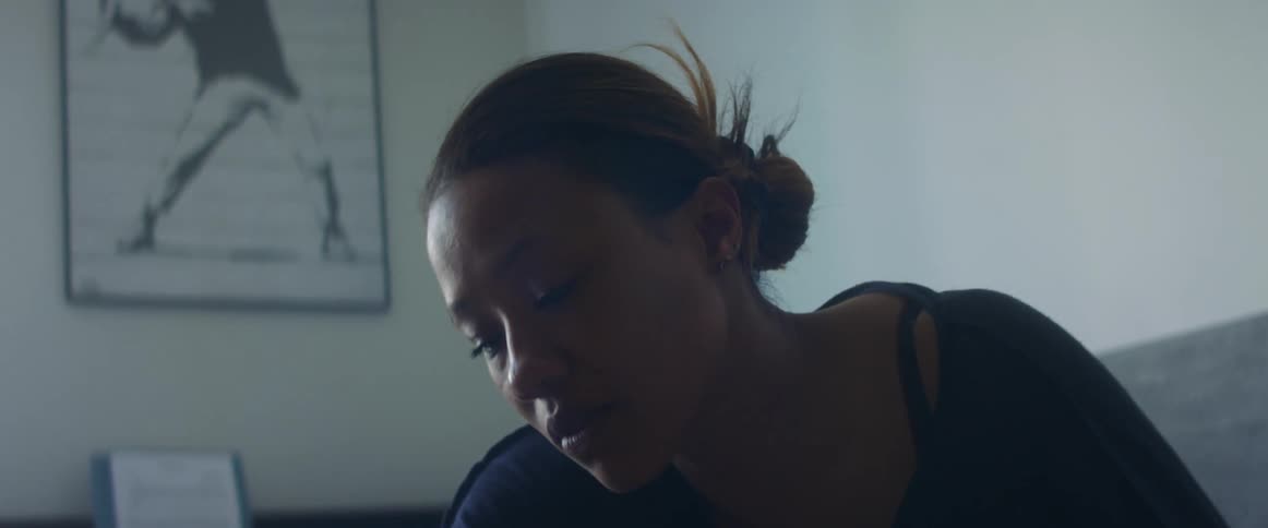 A woman in a room with a picture frame and a wall in the background