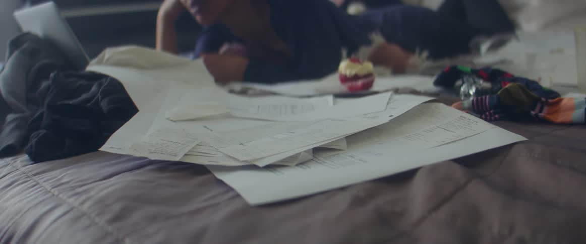 Receipts over the bed near a woman using a laptop