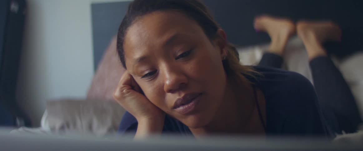 A woman is resting and laying on a bed