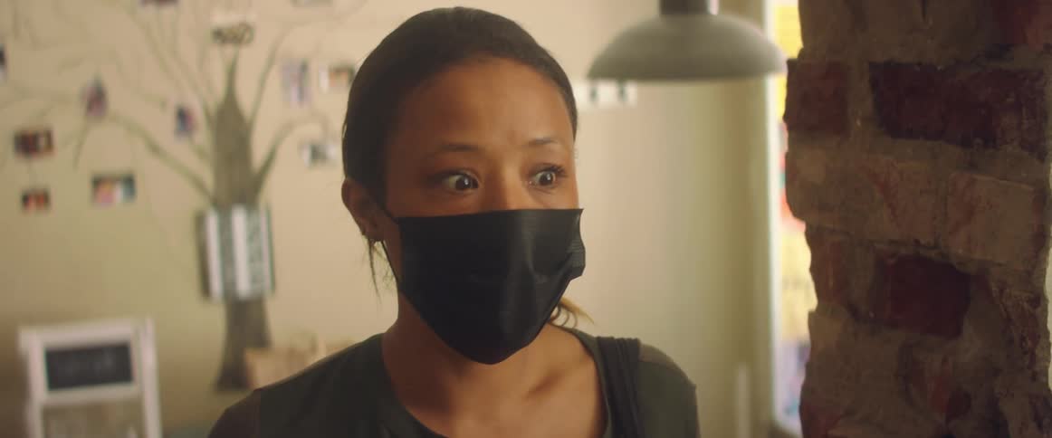 A woman walks up a few steps inside a home and stops to talk to someone