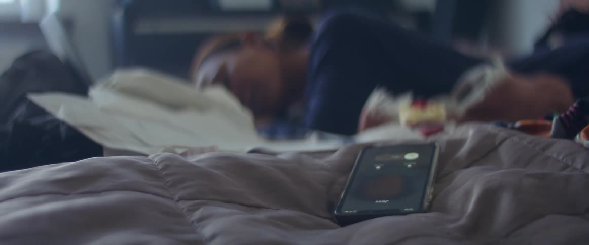 Sleeping woman wakes up to the sound of the phone ringing over the bed