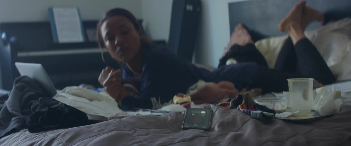 Woman laying in bed next to a laptop wakes up to a phone call