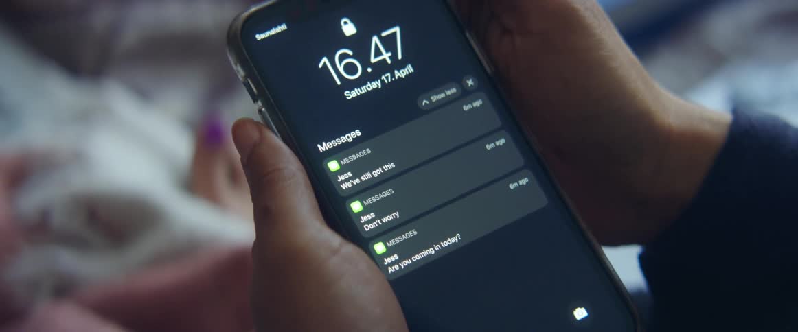 A person taps the screen of a smartphone to expand the list of notifications on the display