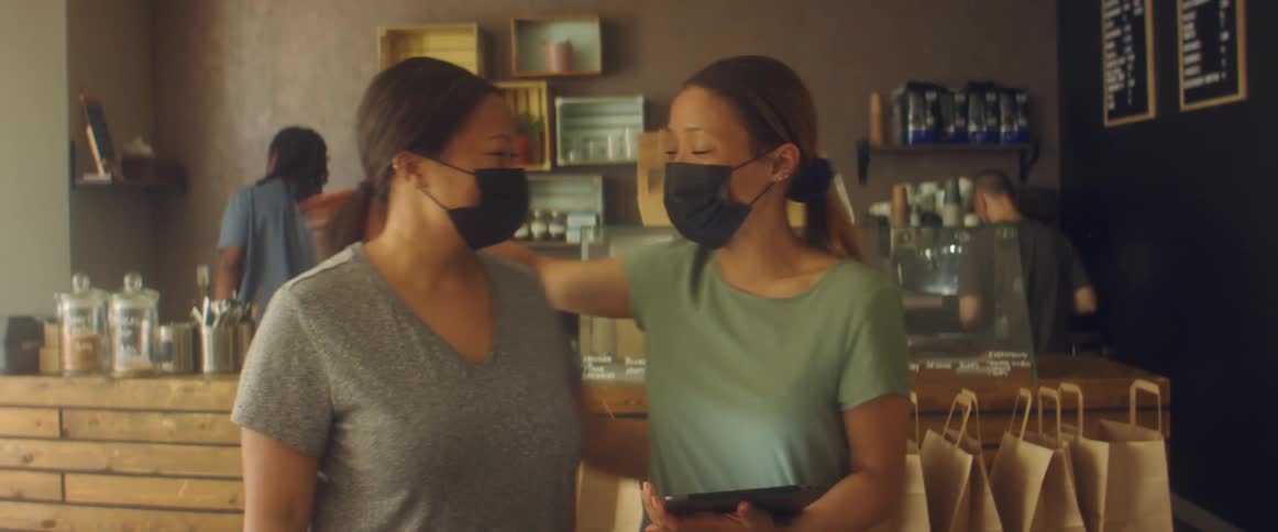 Shop workers wearing black face masks preparing an order to go