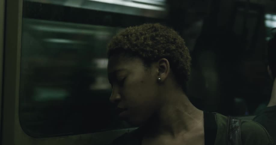 A woman riding on the subway is asleep with her head resting against the window