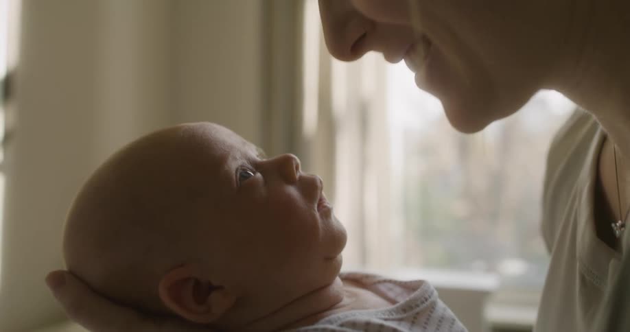 A mother smalls and touches her nose to the nose of her young baby