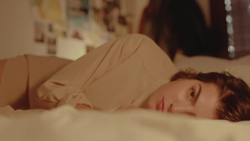 A woman blinks as she rests in bed