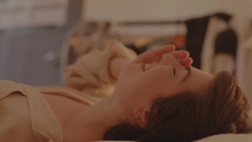 A woman in a room laying in bed with a wall and a door in the background