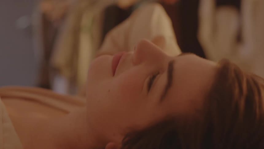 A woman is smiling as she rests in bed