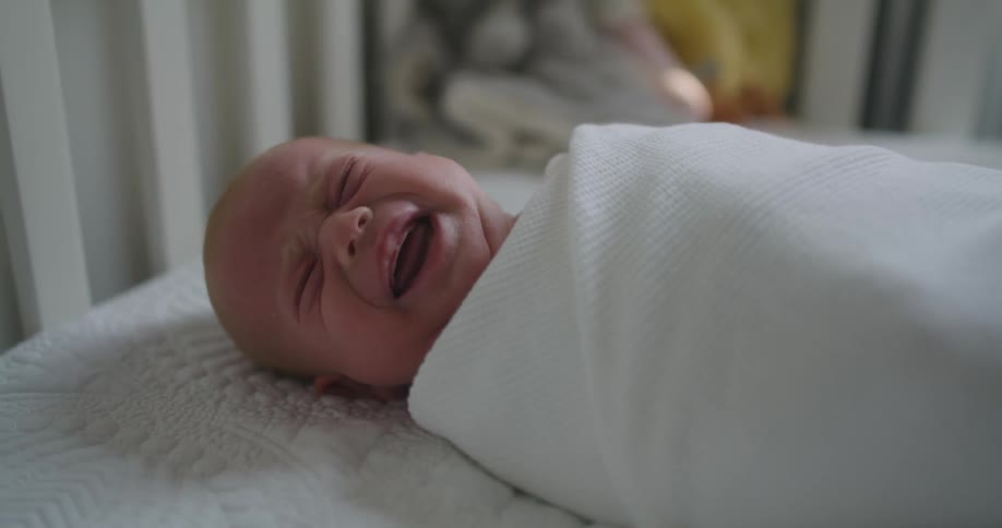 A baby crying while laying in a crib