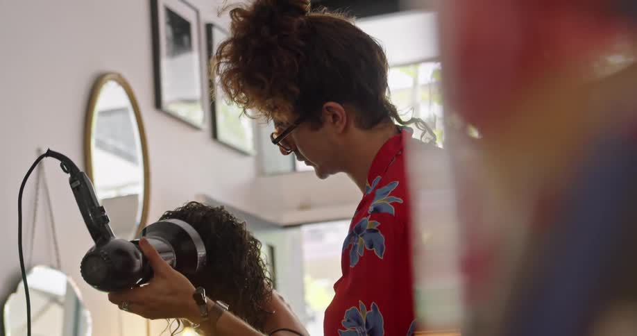 Stylist drying the curls on a clients head in a salon