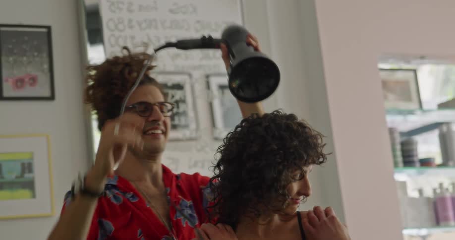 Stylist joking and smiling with a client while giving a haircut at the salon