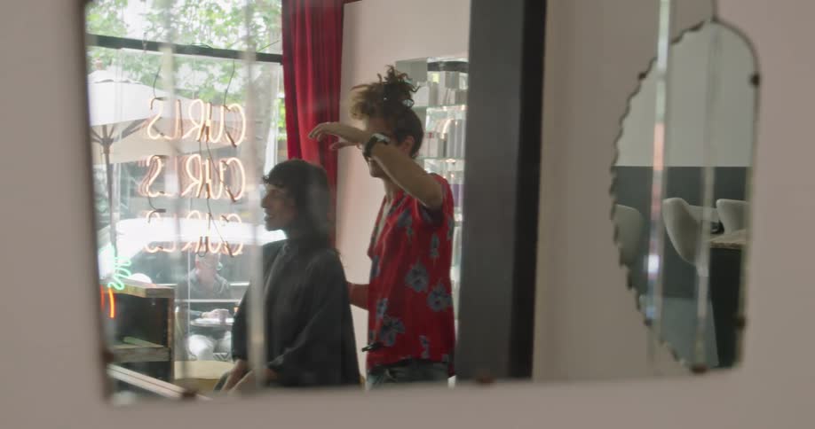 Stylist joking and smiling with a client while giving a haircut at the salon