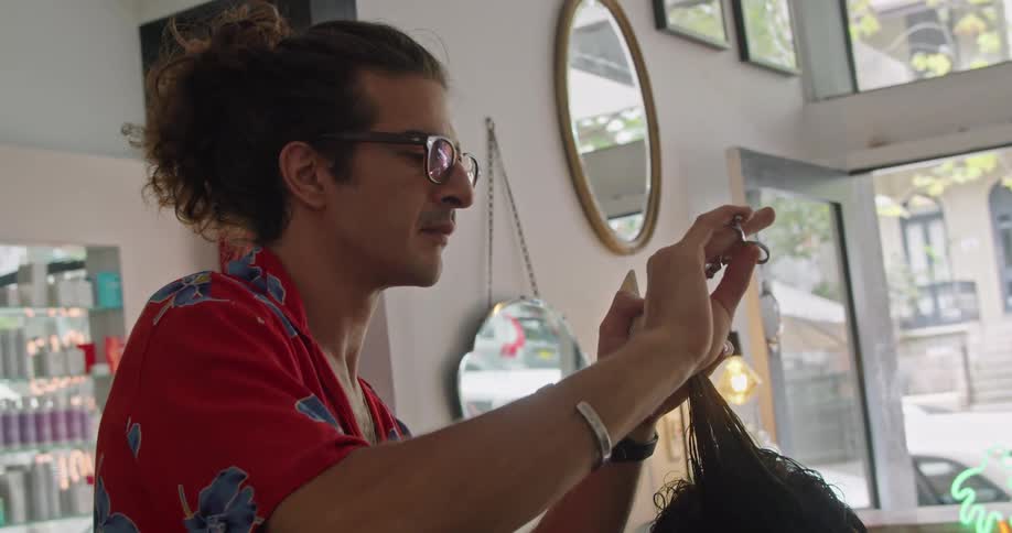 A man with glasses in a hair salon with a wall and a mirror in the background