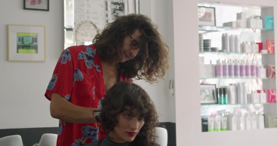 Stylist puts a cape over a client and starts working on a haircut