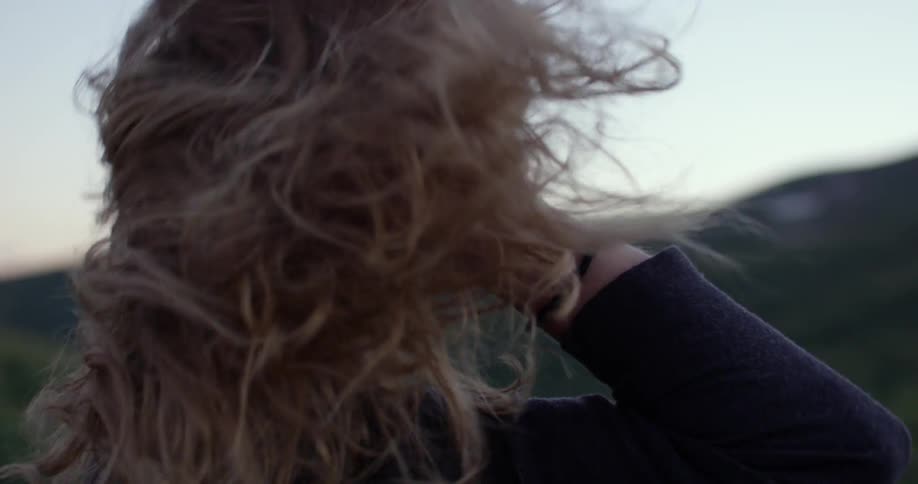 Woman fixing hair in windy mountain