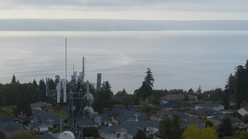 Reveal of a 5G tower near homes in a small town neighborhood along a bay