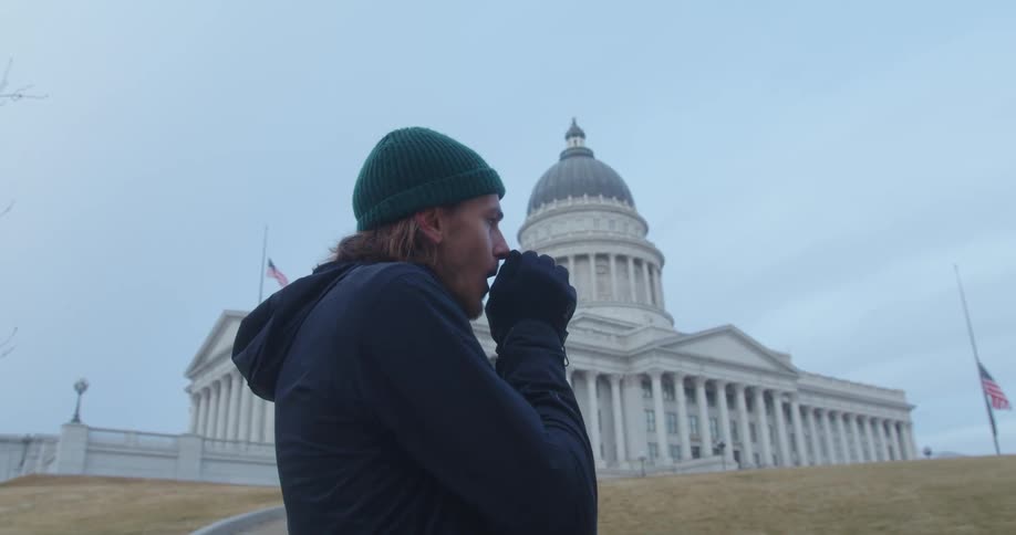 A man is warming up his hands in front of the government building