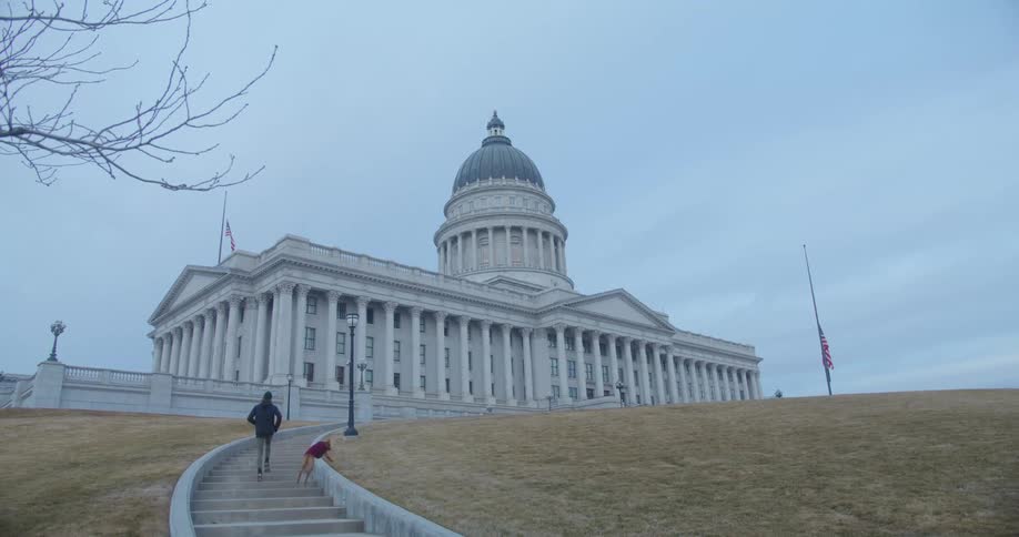 A man runs with his dogs up the steps towards a government building