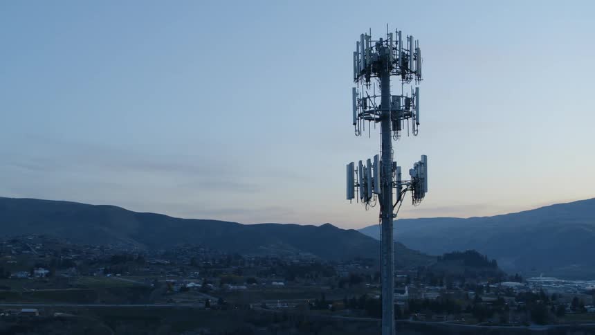 Clockwise orbit around a 5G cell tower high above a mountain valley community