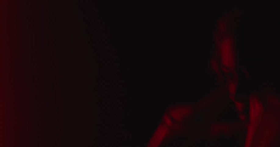 Woman moves and sways in club alternating between darkness and lights in various shades of red