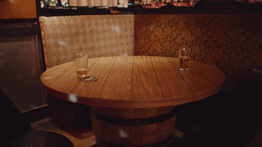 A room with two glasses on a table with coasters with a wall in the background