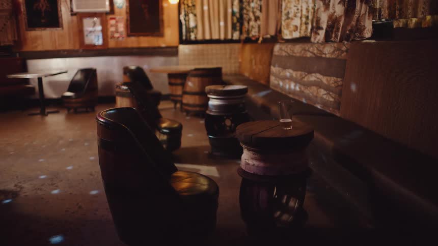 A bar with chairs and tables with a wall and curtains in the background