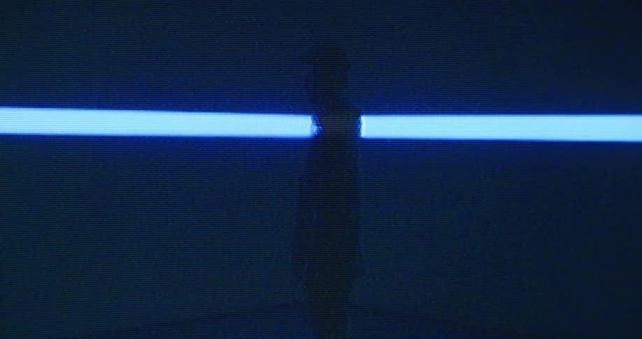The silhouette of a man in a cap in profile goes static in blue and white projected light