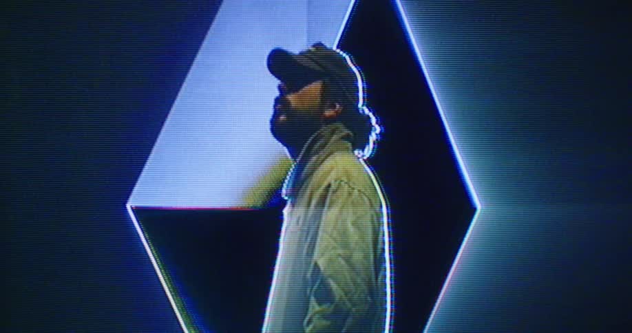 Digital effects occur to image of man wearing baseball ca a and jacket on large screen