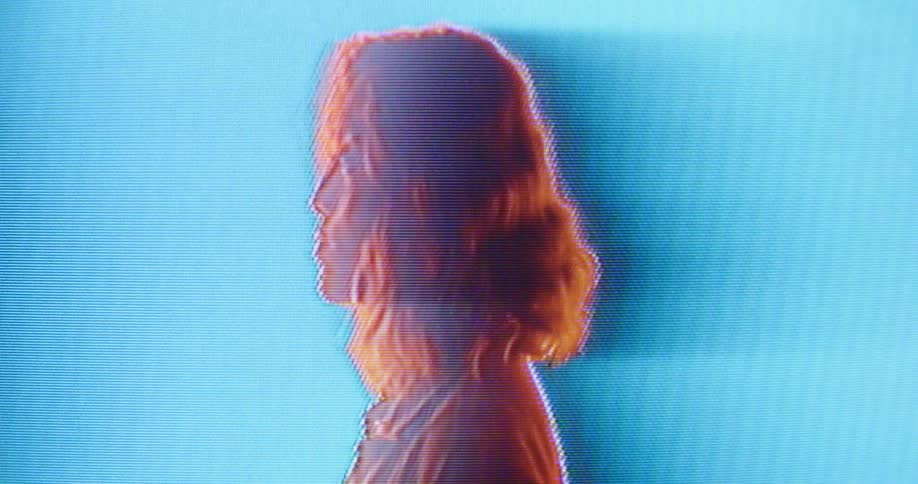 A woman standing in a room with a screen in the background