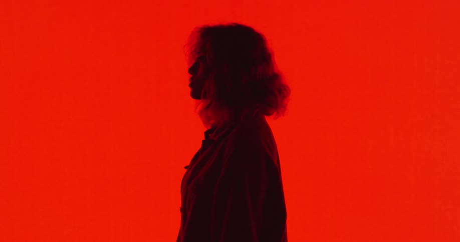 A woman stands in front of a lit up bright red wall