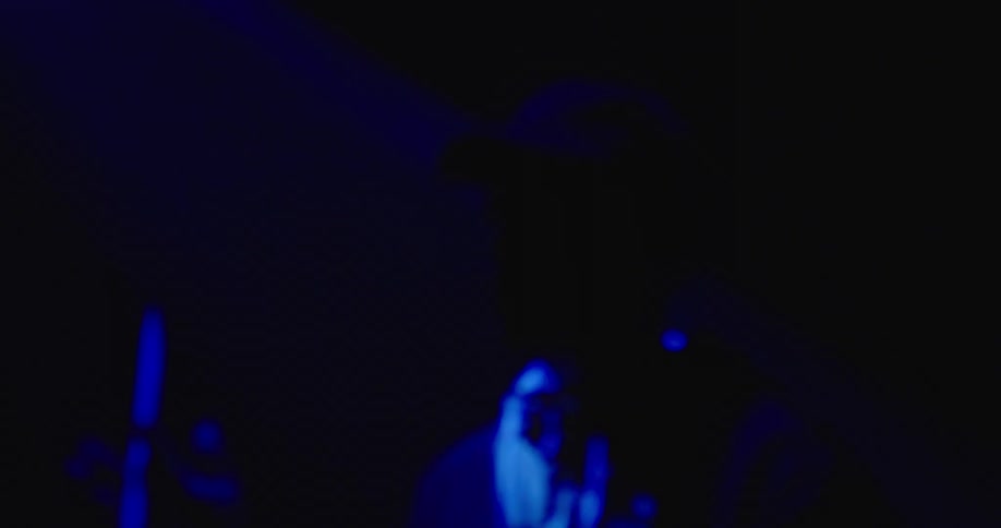 A man is playing drums on the dark stage