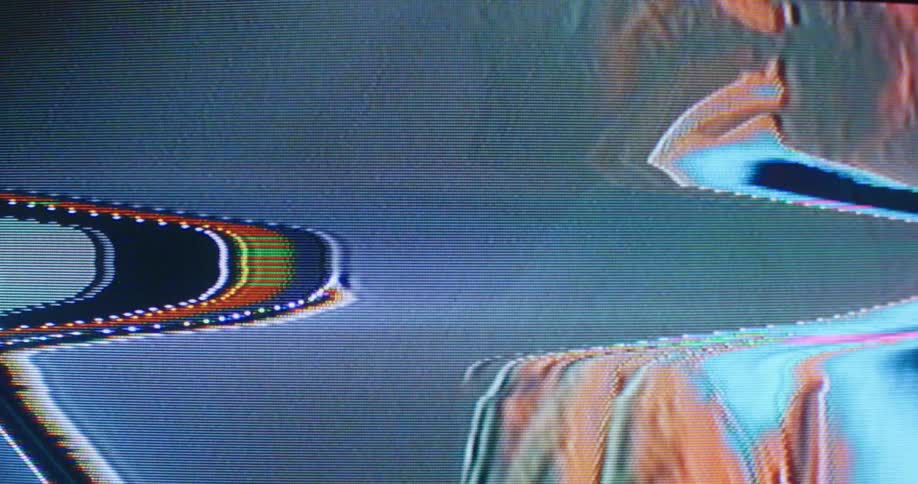 Static and distorted footage shows a man standing in a baseball cap under a spotligt