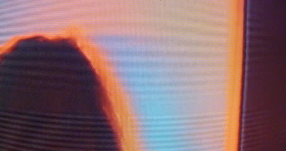 A woman runs her hand through her hair as she stands in a room with flashing digital displays that turn to static