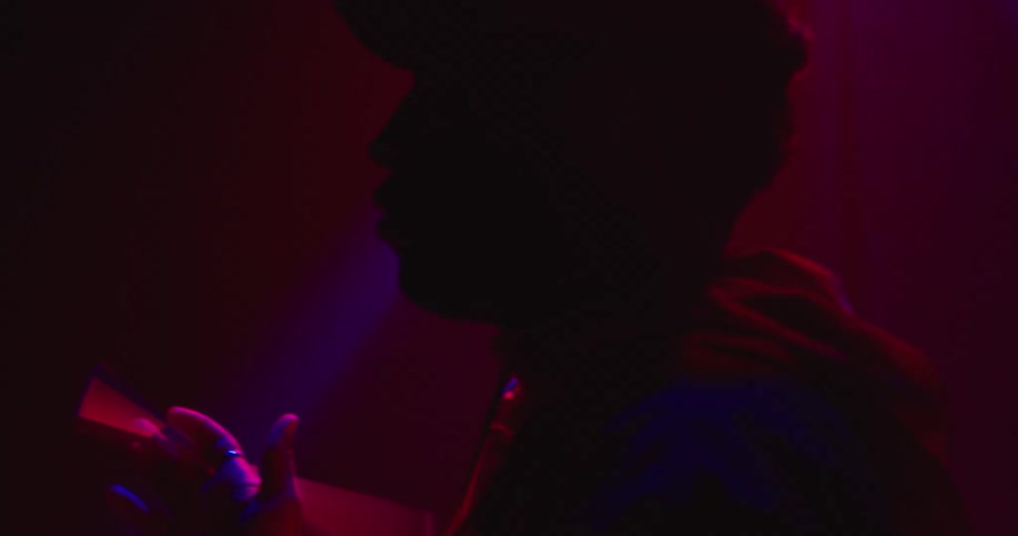 A man is playing the drums under the flickering lights