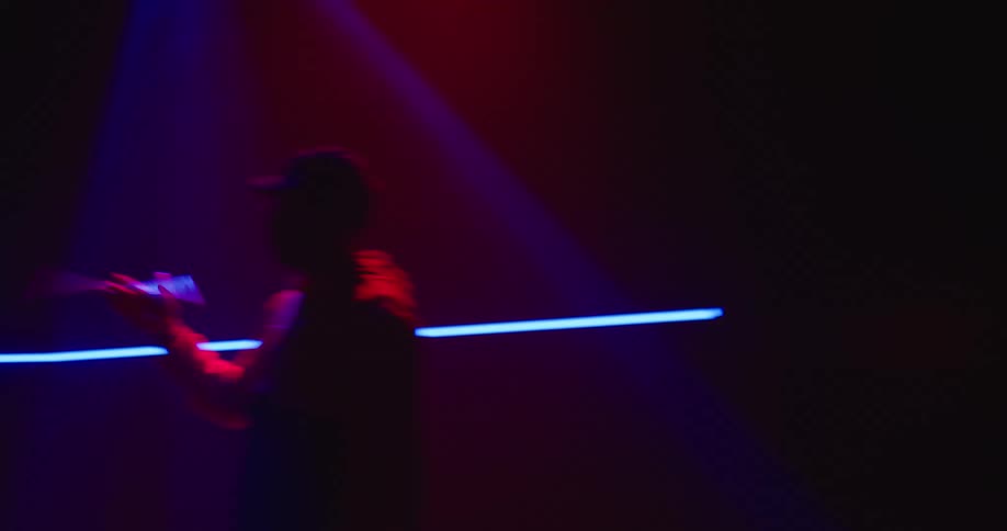 A man is spinning his drum stick under the spotlight