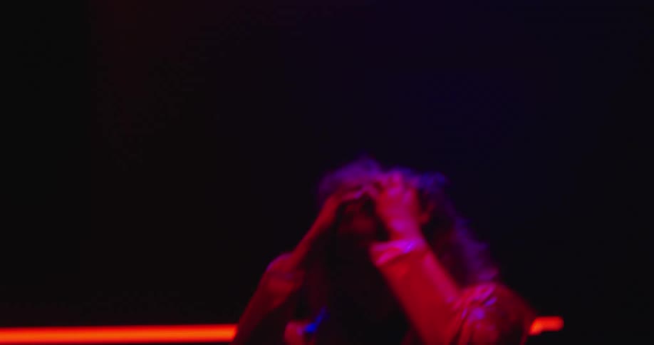A woman brushes back her hair under the flashing lights