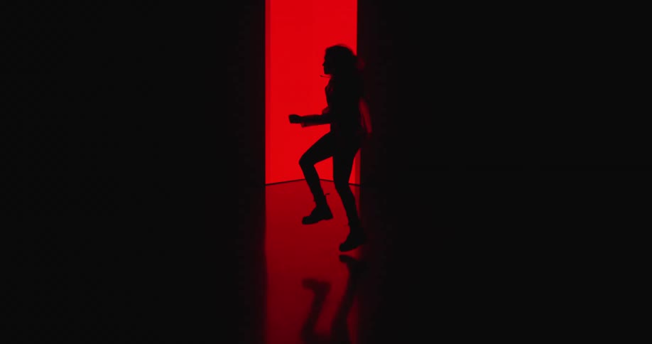 A silhouetted woman dancing in front of a glowing red wall