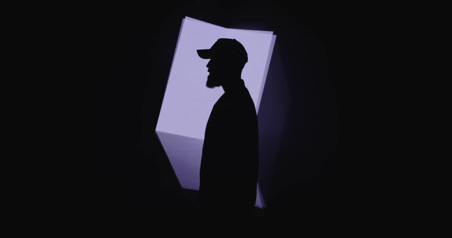 A silhouette man standing in front of a rotating digital cube