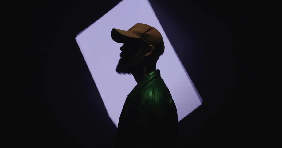 A man is standing in a room and wearing a hat