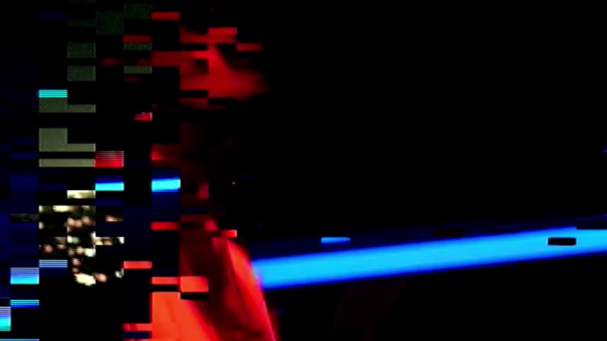 A man with a hat twirling a drumstick in a room with a screen in the background