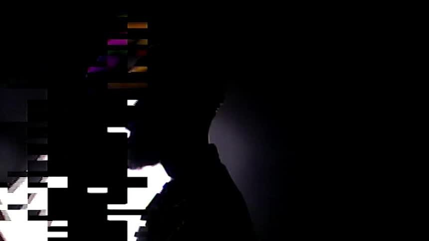 A silhouetted man standing in front of a rotating digital cube