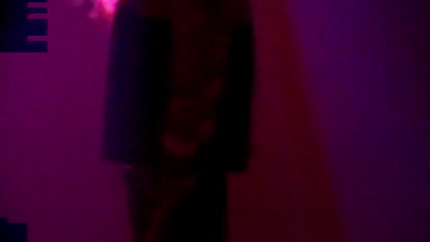 Musician twirls drum stick standing under changing colored lights