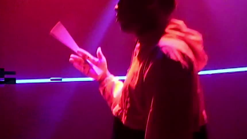 A drummer spinning a drumstick beneath flashing lights on a stage