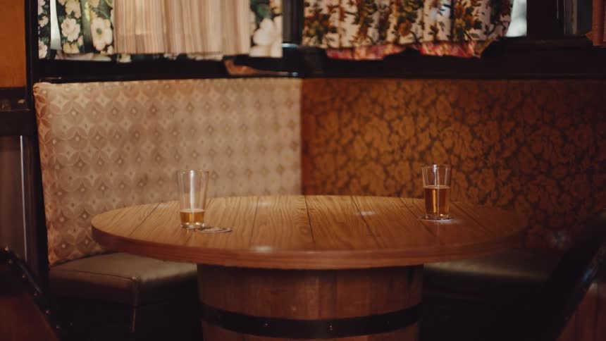 Two glasses of beer sit on a table in a restaurant