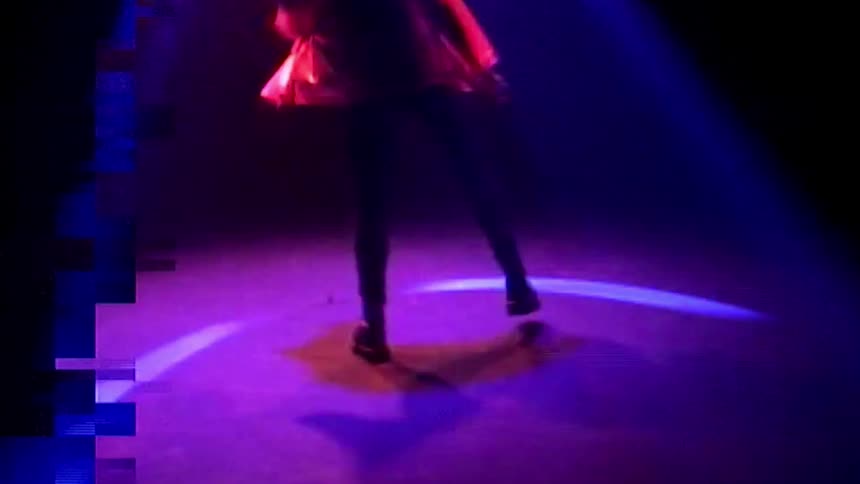A woman is dancing under the spotlight