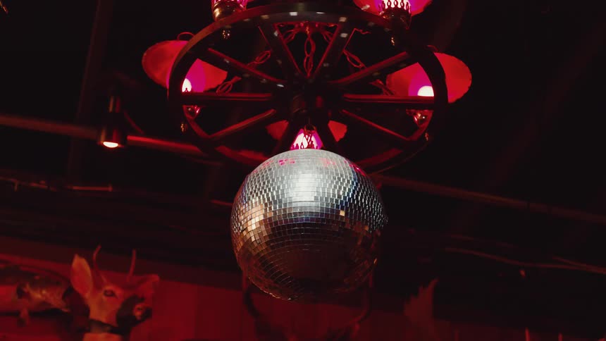 In a dark room with stuffed animal heads mounted on the walls a disco ball spins continuously