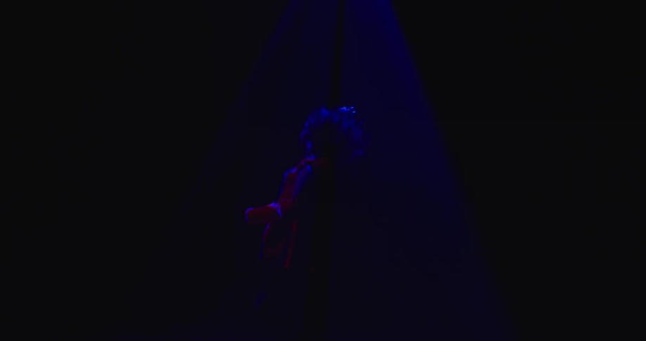 A woman dancing on a dark stage beneath flashing lights